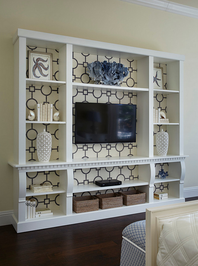 Bedroom Media Cabinet. The master bedroom’s media cabinet, crafted by G R Lytle Woodworks, displays Phillip Jeffries wallpaper and coastal accessories. Intricate detail shows in a lattice urn from Marie Antoinette’s, while shell bookends from Palm Beach Regency flank books from E. Lawrence in Atlanta. JMA Interior Design. 