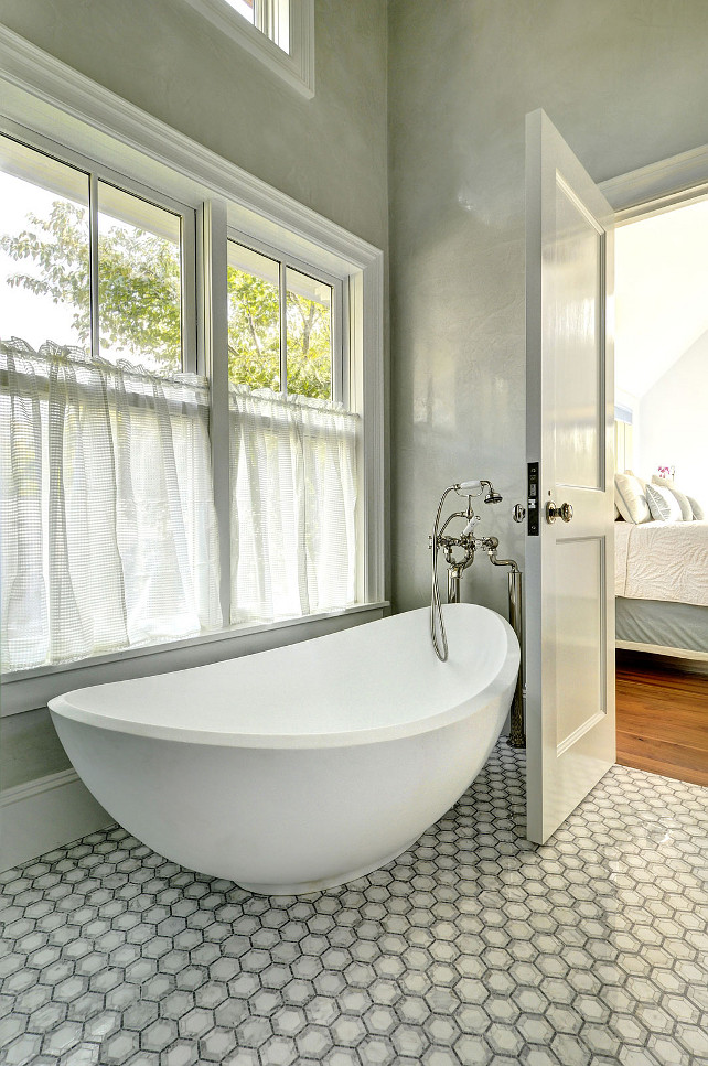Bathroom Freestand bath. The bathroom features walls clad in gray marble, windows dressed in gray pinstripe cafe curtains and a modern egg shaped tub paired with a floor-mount vintage style tub filler. Bathroom freestanding bath ideas. #Bathroom #Bath #FreestandingBath John Hummel and Associates.