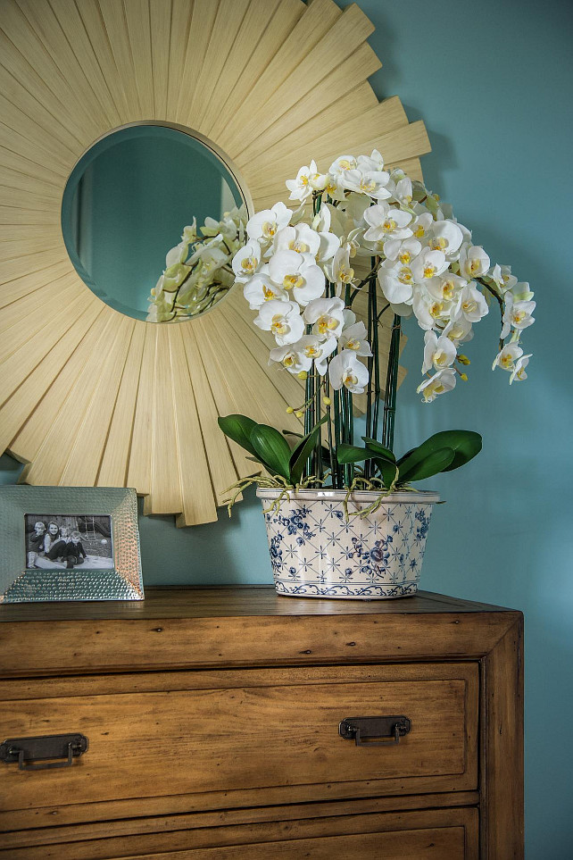 Bedroom Decor Ideas A rosette mirror complements the blue walls, emphasizes warmth from the wooden chest and highlights yellow accents in the floral arrangement. #BedroomDecor