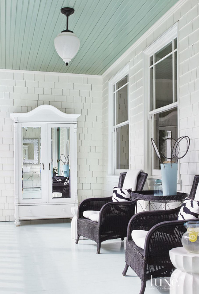 Blue ceiling porch. Blue ceiling porch paint color. A painted antique armoire anchors the front porch with blue ceiling. #Blue #Ceiling #Porch #PaintColor Julie Carabello.