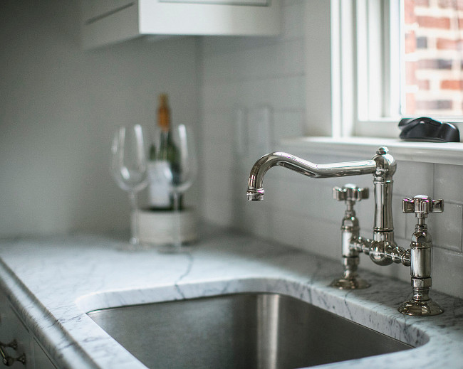 Bridge Faucet. Kitchen Bridge faucet. Kitchen features classic Bridge faucet, white and gray marble countertop, stainless steel sink and white subway backsplash. #Kitchen #Bridgefaucet. JackBilt Homes.