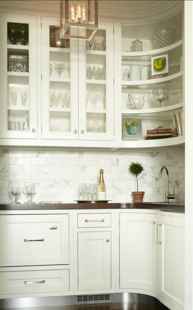 Butler's Pantry. Butler's Pantry Ideas. Butler's Pantry Cabinet. The kitchen features a jewel-box of a butler's pantry. The sink was placed in the corner so that all the appliances such as the bar refrigerator and dishwashing drawers fit into the space. A mix of open and glass fronts on the cabinetry keep the room from feeling boxy. The radius curve of wall and base cabinet allows the eye to glide around the room. #ButlersPantry 