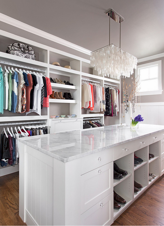 Closet. Dressing room closet with island. This closet features 3cm Bianco Carrera Marble, oak floors, Restoration Hardware Round Glass Knobs on the cabinets, and a large West Elm white capiz shell pendant to top it off. Paint Color is BM Revere Pewter. #Closet #dressingRoom Paint Color is BM HC-172 Revere Pewter. 