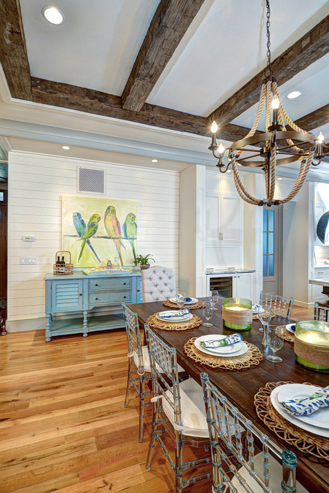 Dining Room Design. Dining room Artwork. Dining room beamed ceiling. Dining room blue buffet. Dining room blue sideboard. Rectangular dining table. Rope chandelier. Rustic wood beams. Tufted chair