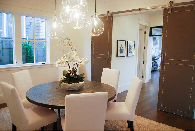 Dining room barn door ideas. Transitional dining room with custom barn door. Stunning custom barn door fabricated in leather and nailhead. #diningroom #barndoor