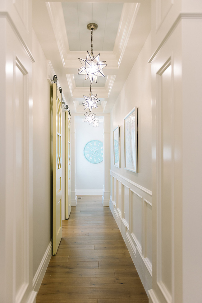 Hallway Ideas. Hallway with paneled walls, tray ceiling with planks painted in blue, star pendant light and barn door leading to laundry room. Four Chairs Furniture.