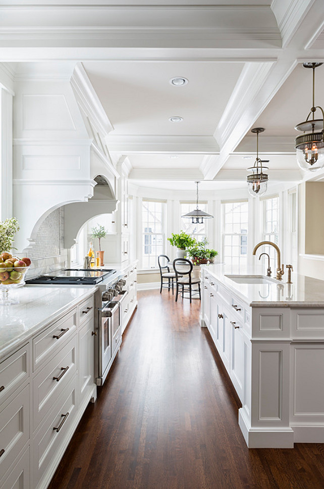 Kitchen Cabinet. Kitchen features a pair of The Urban Electric Co Dover Bell lights illuminating a long center island topped with white marble. #Kitchen #KitchenLighting Casa Verde Design.