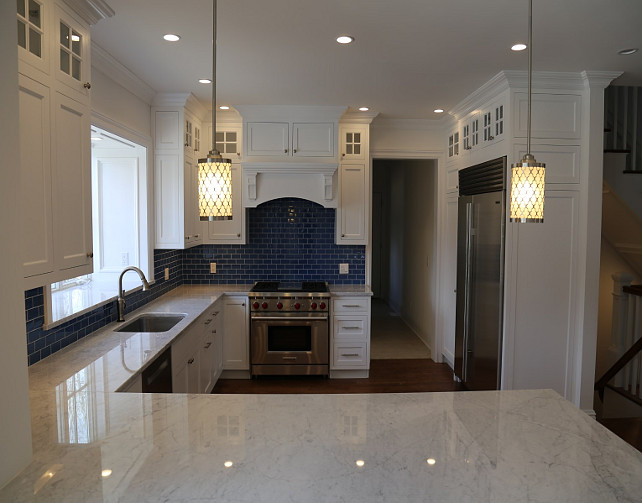 Kitchen with white kitchen cabinets and blue tile backsplash. Blue and White Kitchen. Via Sotheby's Homes.