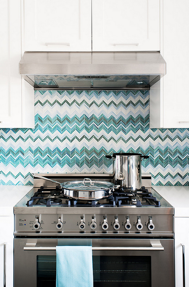 Kitchen. Backsplash. Blue chevron backsplash, chevron backsplash, green chevron backsplash, range hood, stainless steel, stainless steel range, white cabinets, white countertop. Backsplash is a custom designed glass tile. Jute Interior Design.