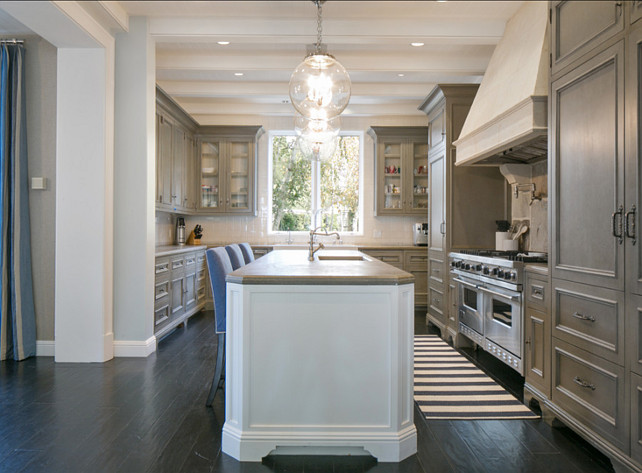 Kitchen. Gray Kitchen Ideas with hardwood floors, pendant lighting above large kitchen island. This is a fabulous gray kitchen with custom cabinets, dark hardwood floors and a very sleek kitchen island. I like the contrast of gray cabinets with a white island. The gray countertop ties the island with the rest of the space together. Hanging glass globe pendants above the island keep the space fully transparent. Pendants are by "Remains Lighting". #Kitchen #GrayKitchen