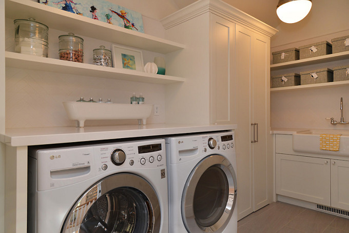 Laundry room with herringbone tile backsplash, gray tile floors, white cabinet, open shelves and farmhouse sink. #laundryRoom Sunshine Coast Home Design.