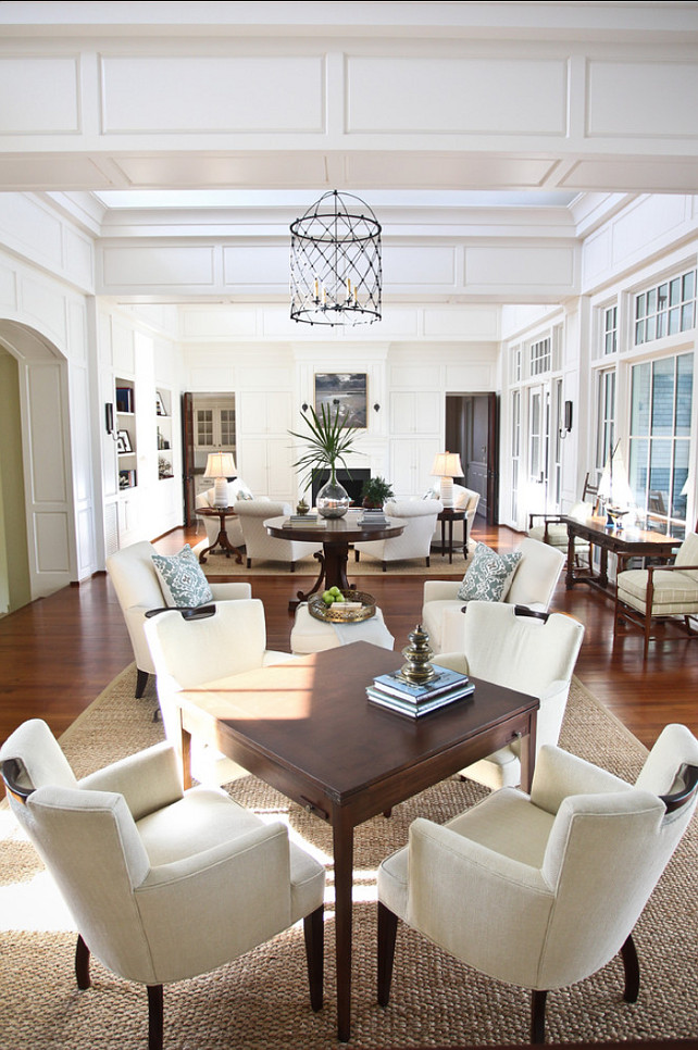 Living Room. Elegant living room with perfect furniture layout. A similar color is Farrow and Ball Slipper Satin. The large living room was divided into several areas: game table, reading area, center table and main sitting/TV area. All white/neutral upholstery is tempered with the use of textures and wood. A custom game table has cup holder pull-outs to keep the card playing surface free of clutter. The bookshelves boast a collection of found items, family photos and books. #LivingRoom #LivingRoomDesign. #LivingRoomIdeas #LivingRoomLayout #LivingRoomFurniture