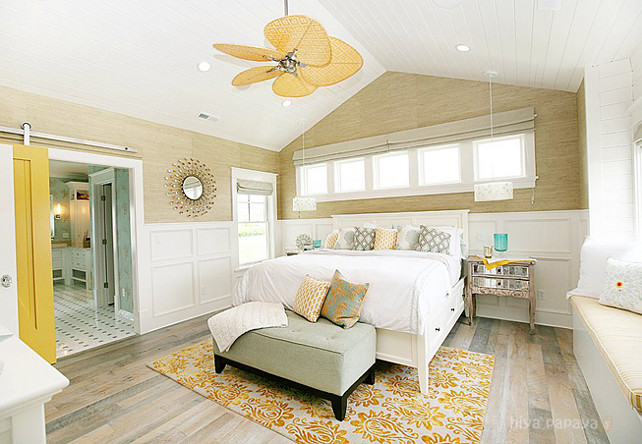 Master Bedroom. Beach Style Master Bedroom. Inspiring master bedroom design with grasscloth wallpaper, wall panels, sunburst mirror, sliding barn door, beadboard ceiling, white wood bed, tufted bench, mirrored nightstands and built-in window seat. Coastal Master Bedroom. #MasterBedroom