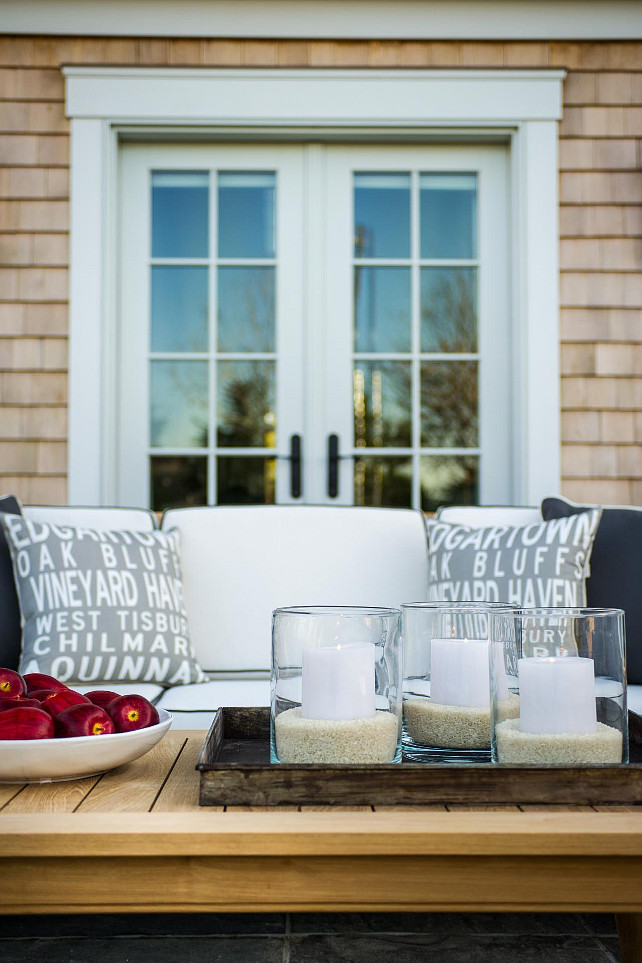 Patio Decorating Ideas. The teak furniture and white cushions echo the home’s neutral coloring, serving as a complimentary extension to the Cape Cod abode. #PatioFurniture #PatioIdeas