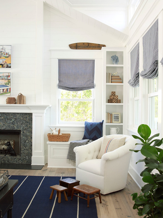 Reading Nook. Reading Nook with built-in window seat and comfortable white tufted chair paired with a collection of vintage stools placed atop navy blue striped rug. #ReadingNook #Furniture Paint Color: "Pratt and Lambert Designer White". Burnham Design.