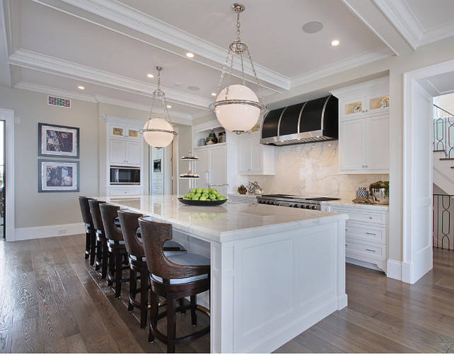 Seagrass Back CounterStool. Fantastic white kitchen with large white island, topped with marble countertop, seagrass counterstools, marble slab backsplash and a black and stainless steel hood. White kitchen with Seagrass Back CounterStool. White kitchen with five Seagrass Back CounterStool. #SeagrassCounterStool #Seagrass #SeagrassBackCounterStool Spinnaker Development.