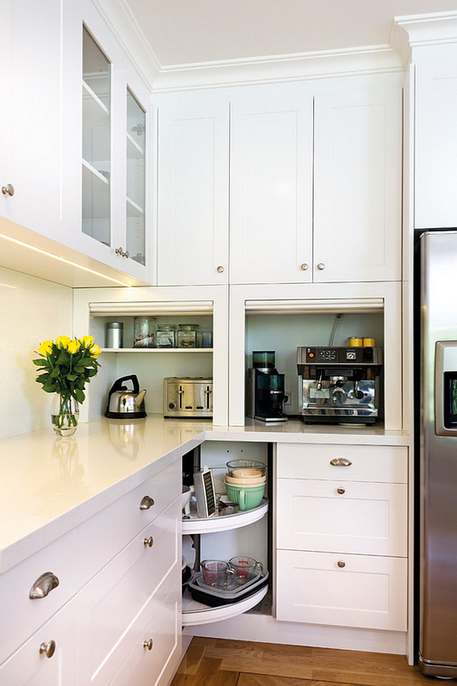 Small Kitchen Cabinet Plan. Kitchen bin pulls, cabinet lazy susan, cake stand, cup pulls, glass front cabinets, glass backsplash, lazy susan, shaker style cabinet, stainless steel, tambour, white counters. Countertop is Caesarstone Snow. Kitchens by Peter Gill.