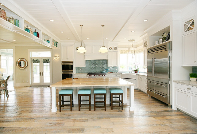 White Kitchen Ideas. Open kitchen design with beadboard ceiling, farmhouse sink, blue glass tiles backsplash, schoolhouse pendants, white custom cabinets, white countertops, pot filler, white kitchen island, butcher block countertops, espresso stained counter stools with blue vinyl tufted cushion. White Kitchen. #WhiteKitchen